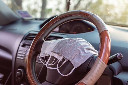 Different types of hygienic masks, both white and gray, are placed in the steering wheel of the car,...