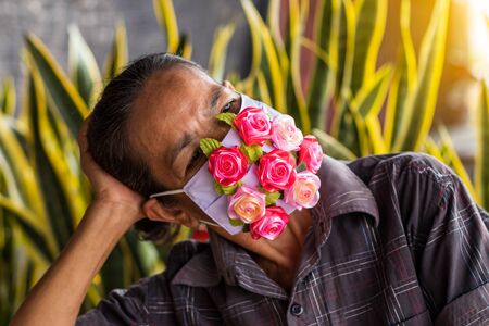 Close up shot of a beautiful fake rose attached to a mask made of white cloth and is worn on the face of a Thai woman.の写真素材