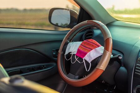 Close-up shot of a different mask that is placed inside the steering wheel, inside the car, and the sunlight on rural roads in the afternoon.の写真素材