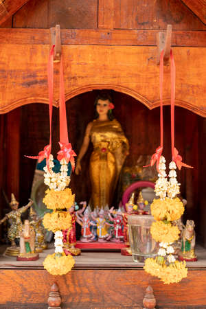 Close-up of a garland of flowers hanging from the wooden hooks of the shrine, the old wood with...