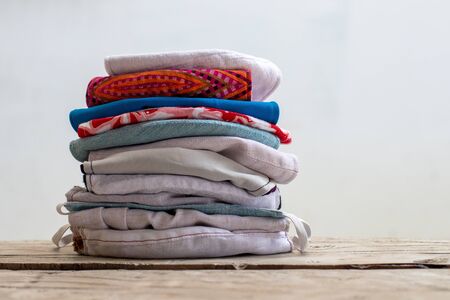 Numerous fabric masks, Thai motifs and different colors, folded and stacked on a brown wooden floor...