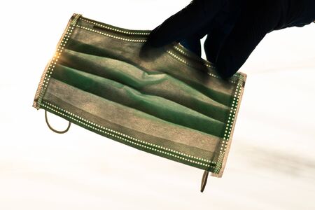Isolated backlit, close-up shots of hand in gloves held up, holding a green mask over the louvers...