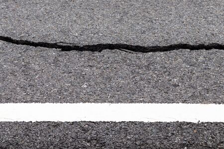 Close-up shot of the side, background, paved surface of a cracked road, a long way near a white rural line.の写真素材