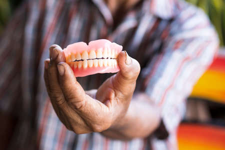 Close-up of a denture in the hand of a Thai elderly man protruding to show its appearance.の写真素材