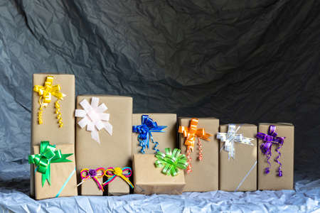 Numerous rows of gift boxes made of paper and bow ties are placed inside a gray canvas waiting for...