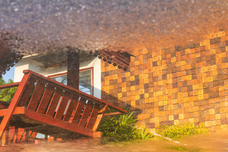 Close up Abstract background of water reflection on street floor, close to brick and wooden shed walls of a building.の写真素材