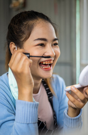 Close-up portrait, face of a beautiful Thai woman adorned with eyelash curlers and laughter and cheeky posture.の写真素材