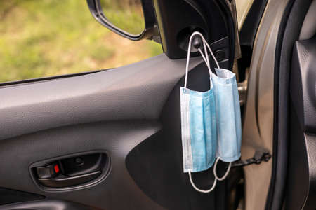 Close-up, two blue face masks suspended inside the car preparing to be worn against the virus.の写真素材
