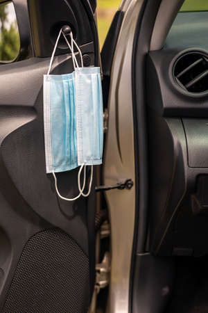 Close-up, two blue face masks suspended inside the car preparing to be worn against the virus.の写真素材