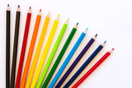 Isolated background, many colorful pencils are scattered in a rainbow-like sequence on a white piece of paper.の写真素材