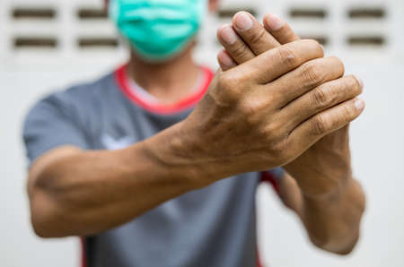 Close-up of two hands of a man squeezing in a massage due to nerve endings numbness in guillain barre syndrome, a possible side effect of the COVID-19 vaccination.の写真素材