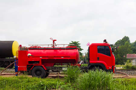 A firefighter stands behind a red fire engine waiting to extinguish the fire on a grassy road near a...