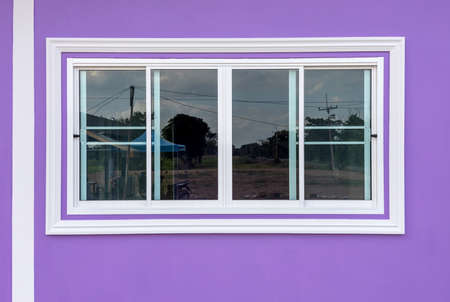 A sliding window background with reflections in a white concrete frame is set against the purple walls of a contemporary house.の写真素材