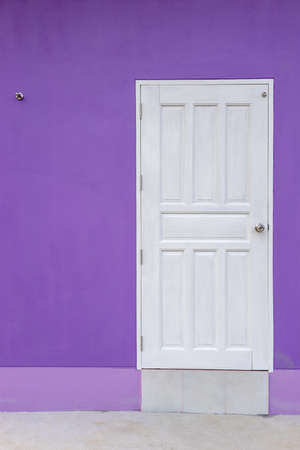 A white wooden door background is set against a beautiful purple concrete wall that forms part of the contemporary style home.の写真素材