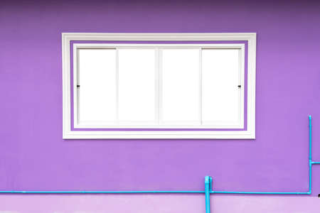The white concrete window frame background, which is sliding against a purple wall and blue PVC water pipes below, is a common sight in modern contemporary house construction.の写真素材
