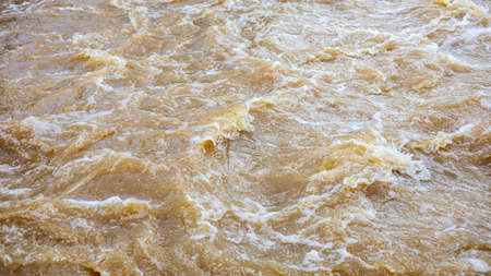 Background of turbid brown tidal wave surface which turbulently floods the overflow weirs, often seen in rural canals in Thailand during the rainy season, causing flash floods.の写真素材