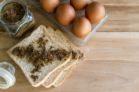 A close-up view from above, three slices of bread smeared with herb jam are placed on a wooden floor...