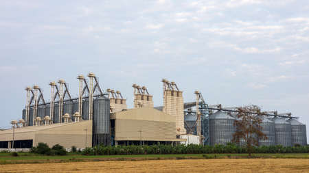 View of an old factory building used as a barn for steaming rice grains abandoned on the harvested rice fields of rural Thai agriculture.の写真素材