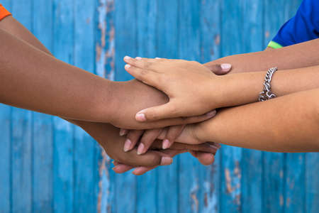 A close-up view of three Thai children holding hands in friendship and working together for success...