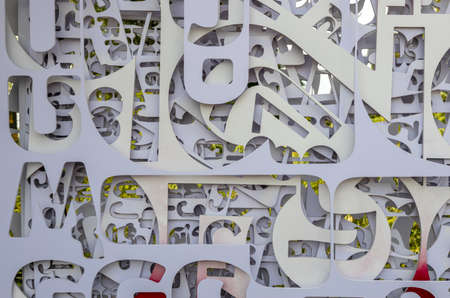 Fragmented backgrounds of white plates, which have been stenciled in letters of various sizes, have been hung overlapped together for disposal or reuse.の写真素材