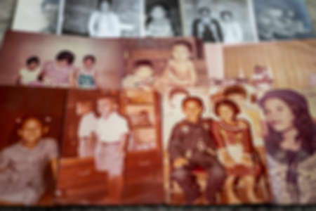 A close-up, blurry, out-of-focus background of old family photos in black and white and sepia lined...