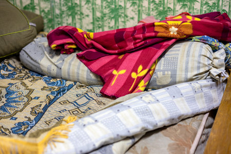 Lots of old, colorful clothes hung chaotically on the iron railings near the closets and baskets in...