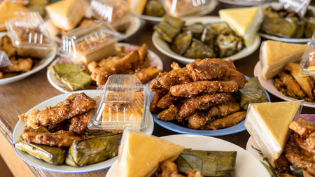Many delicious fried banana snacks packed in plates placed amongst other Thai desserts lined up on...