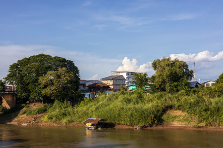 Scenery of many residential houses erected along the banks of the canal river with sky clouds as a beautiful afternoon backdrop in the Thai countryside.の写真素材