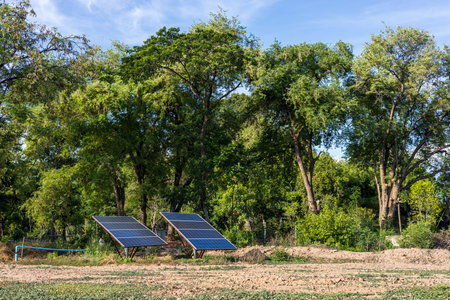 View Two large solar panels are mounted on barren ground for pumping water as an alternative energy...