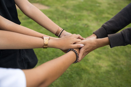 A close-up view of the arms and hands of young male and female friends holding each other together...