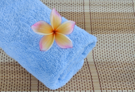 blue towel and plumeria flower on wooden backgroundの写真素材