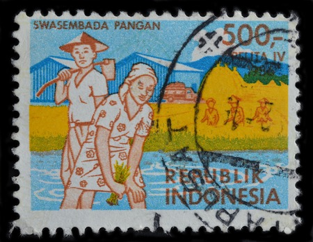 INDONESIA - CIRCA 1986 : postage stamp printed in Indonesia shows farmers working at paddy fields, circa 1986のeditorial素材