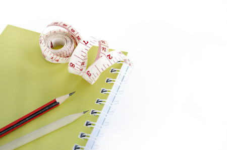 book and pencils with tape measuring isolated on whiteの写真素材