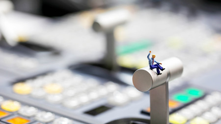Miniature people : businessman sitting on switcher control of Television Broadcast,color buttonsの写真素材
