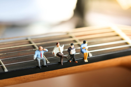Miniature people : Businessman sitting on acoustic guitar. time of relax or music relax concept.の写真素材