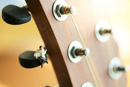 Miniature people : Businessman sitting on acoustic guitar. time of relax or music relax concept.
