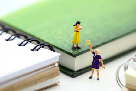 Miniature people : sitting on book using as background education or business concept.
