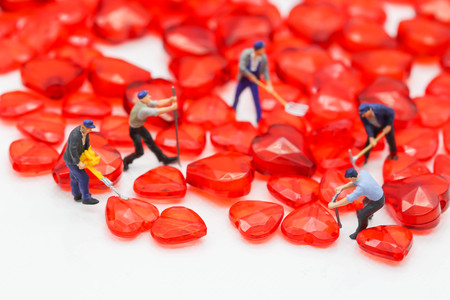 Miniature people : working on red heart isolated on white backgroundの写真素材