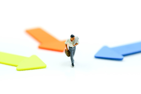 Miniature people: Businessman standing in front of arrow pathway choice using as Business decision...