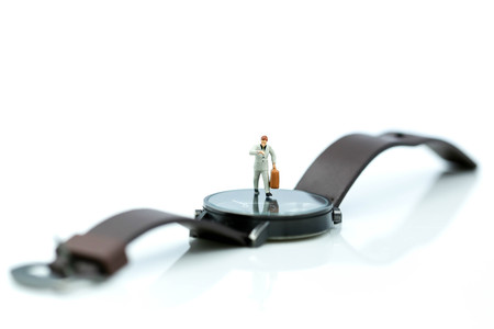 Miniature people : business man looking at watch and walk on the clock background, time business concept.の写真素材