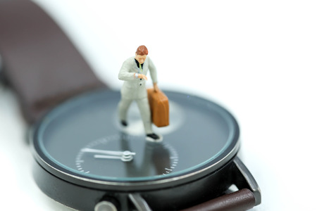 Miniature people : business man looking at watch and walk on the clock background, time business concept.の写真素材