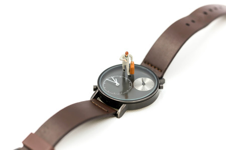 Miniature people : business man looking at watch and walk on the clock background, time business...