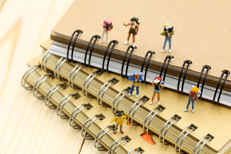 Miniature people :  backpacker and tourist people standing with a book, travel concept.の写真素材