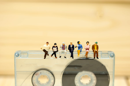 Miniature people : worker and people relax sitting with Audio cassette with magnetic tape.の写真素材