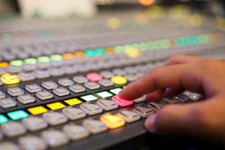 Hands push a button of Switcher buttons in studio TV station, Audio and Video Production Switcher of Television Broadcast.の写真素材