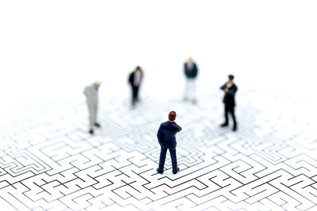 Miniature people: Businessman standing on start point of maze using as background business concept.