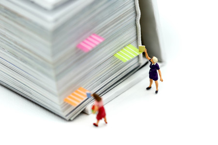 Miniature people : reading stand on book using as background education or business concept.