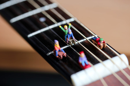 Miniature people : Child  having fun to play slider with acoustic guitar,time of relax or music relax,stationary,education concept.の写真素材