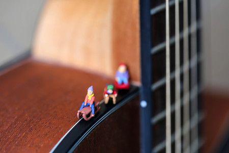 Miniature people : Child  having fun to play slider with acoustic guitar,time of relax or music relax,stationary,education concept.の写真素材