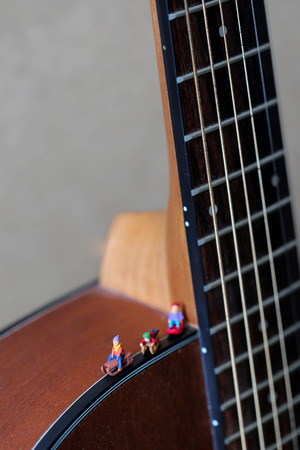 Miniature people : Child  having fun to play slider with acoustic guitar,time of relax or music relax,stationary,education concept.の写真素材